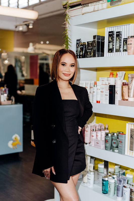 Blaze Hair salon team member standing in front of professional haircare products in Auckland, New Zealand